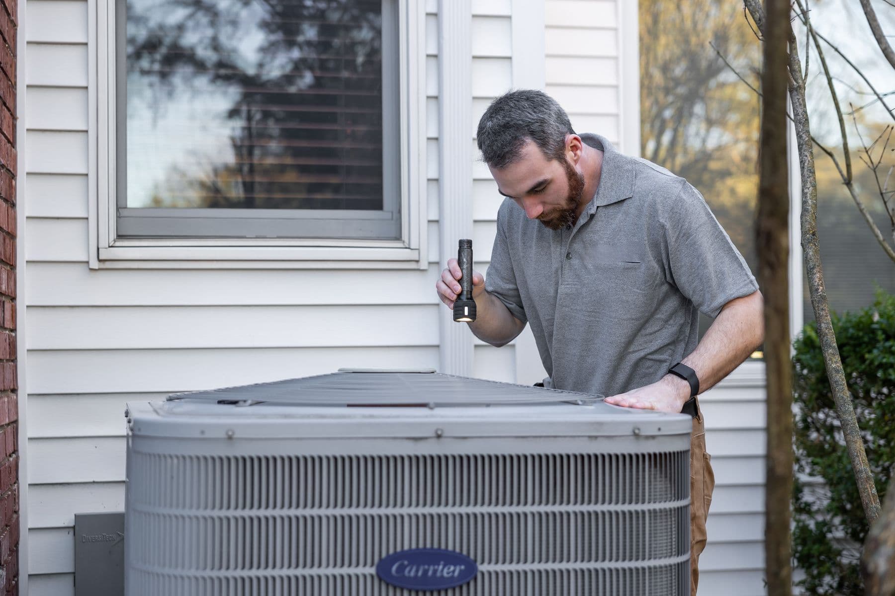 Technician inspecting a residential outdoor HVAC unit